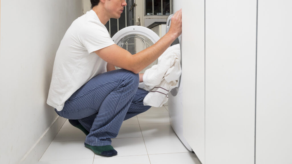 close up man putting clothes washing machine x