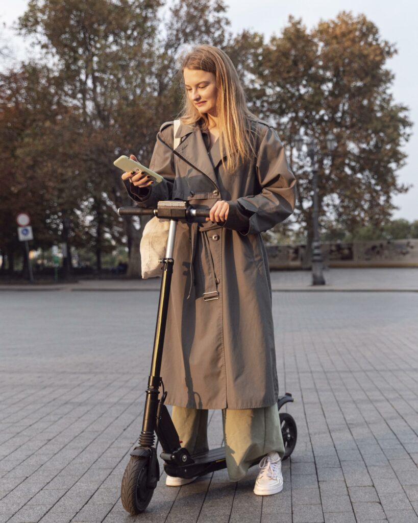 woman checking her smartphone while electric scooter outdoors  x