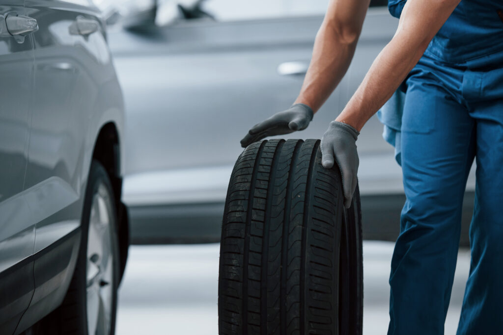 business car repairing mechanic holding tire repair garage replacement winter summer tires x