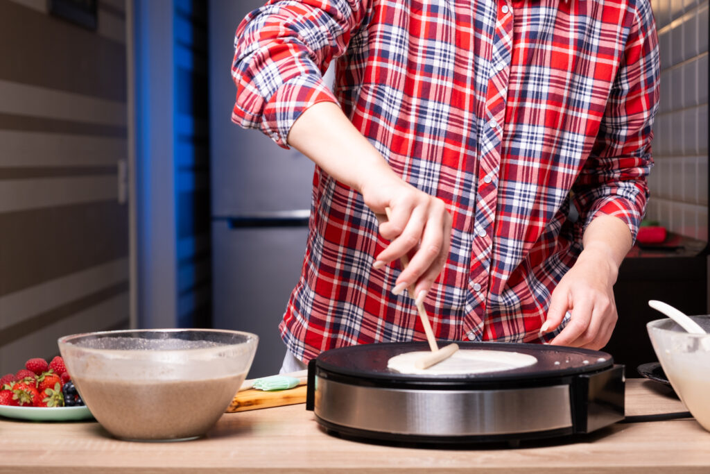 woman cooking delicious crepe electric pancake maker kitchen closeup x